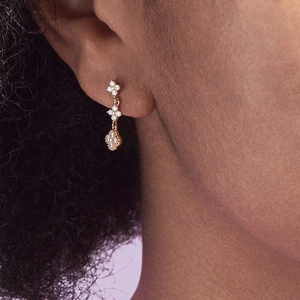Detail of gold petal earrings featuring white cubic zirconia in a triple drop design