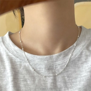 Minimalist 925 sterling silver necklace with tiny white beads shown on a model