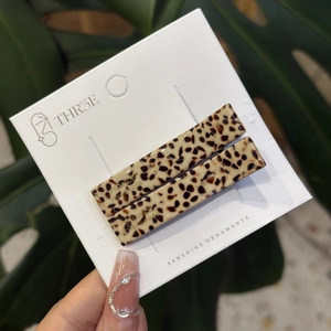 Close-up of beige leopard print acetate hair clips with metal back on white card