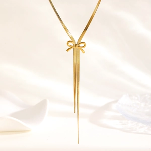 Nahaufnahme der goldenen Schleife an einer Schlangenkette mit asymmetrischen Quasten