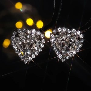 Sparkling crystal heart stud earrings with silver plating shown against a bokeh background