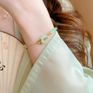 Gros plan d'un collier en perles dorées avec feuille de ginkgo en jade et pendentif ping'an