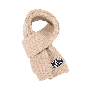 Detailed view of beige knitted scarf texture with Teddy Island bear logo patch