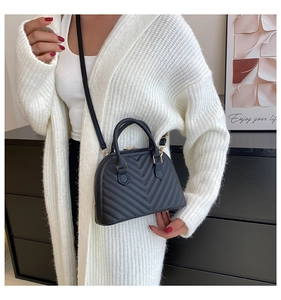 Detailed model shot of black V-quilted handbag with gold hardware and double handles