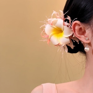 Detailansicht einer tropischen Plumeria-Blüten-Haarklammer mit feinen Federakzenten