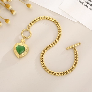 Gros plan du pendentif cœur doré avec pierre œil de chat verte et fermoir à bascule