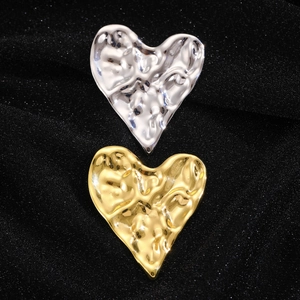 Broche cœur irrégulière en finition or et argent sur un tissu noir texturé élégant