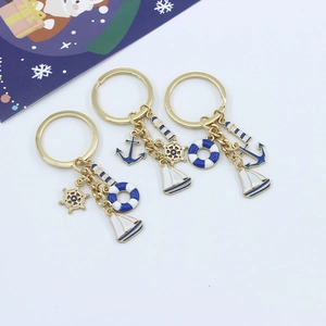 Close-up of nautical gold metal keychains featuring lighthouse, anchor and sailboat charms