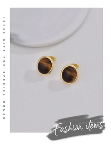 Macro detail of round tiger eye stone stud earring with a polished gold plating finish