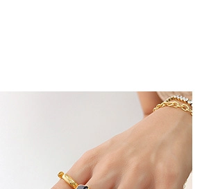 Close-up of gold and black 18k plated titanium rings with layered chain bracelets on wrist