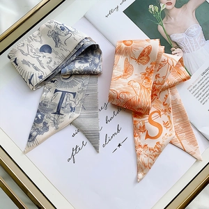 Silk scarf ribbon with letters T and S in blue and orange on a golden tray