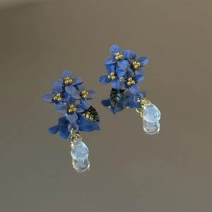 Detail of blue flower earrings with gold stamens and crystal water drop pendants