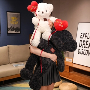 Detail of plush black and white teddy bears with red heart pillows in a home setting