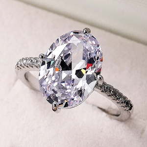 Exquisite silver-colored ring with large oval-cut zircon and pavé diamond band