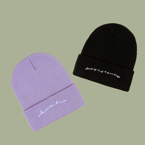 Classic knitted beanies in purple and black colors with white cursive embroidery