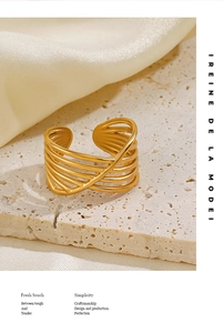 Detailed macro of gold-plated multi-layer crossover ring on minimalist stone texture