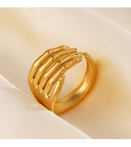 Detailed macro shot of adjustable gold hand-shaped ring on a soft silk background