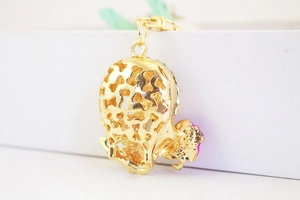 Close-up of golden hollow skull keychain with rose red accents on white background