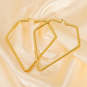 Detailed view of large gold geometric earrings on elegant champagne satin fabric
