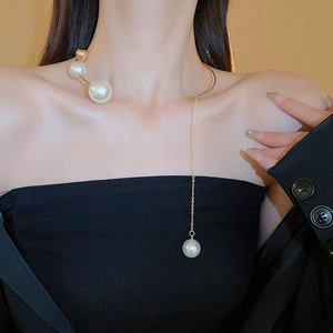 Close-up of golden asymmetric collar necklace with white pearls on a female model