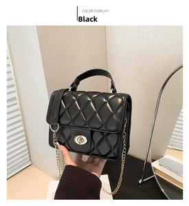 Close-up of black quilted bag featuring a golden twist lock and metal chain strap