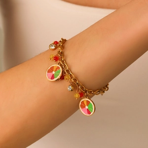 Close-up of gold-plated bracelet with enamel fruit charms and beads on a model's wrist
