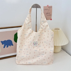 Détail du sac fourre-tout en toile crème avec motifs d'ours roses et étiquette sozakka tissée