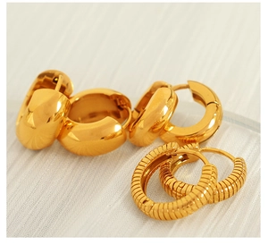 Close-up of gold stainless steel hoop earrings with smooth and ribbed spiral textures