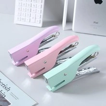 Three macaron-colored staplers in lavender, pink, and mint green on a clean white desk