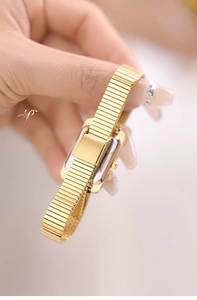Detail of gold-tone women's square watch with flexible metal link strap and polished back