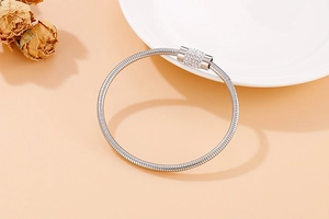 Détail du bracelet en chaîne serpent argentée avec breloque cylindrique pavée de cristaux