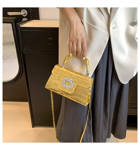 Golden crocodile pattern handbag with rhinestone buckle shown on shoulder for sizing