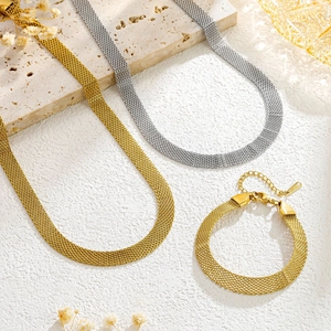 Golden and silver mesh woven choker necklace and bracelet set on stone background