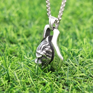 Vintage silver lion head pendant necklace with Viking axe detail on a green lawn