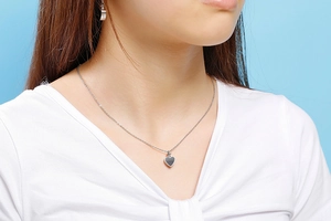 Gros plan d'un collier avec pendentif en cœur porté par un mannequin sur fond bleu