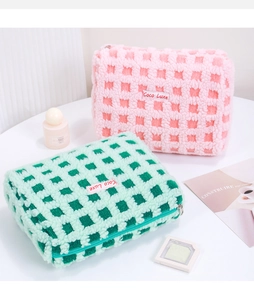 Close-up of checkered plush cosmetic bags with soft waffle texture and metal zipper