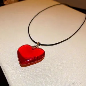 Collier minimaliste avec pendentif cœur en verre rouge et cordon noir sur un support