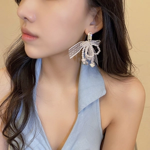 Détail de boucles d'oreilles nœud en dentelle avec perles et cristaux sur un mannequin