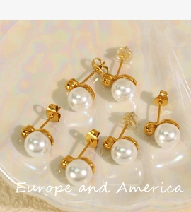 Macro view of three pairs of elegant gold-plated pearl stud earrings on a shell tray