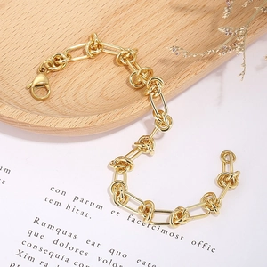 Detail of gold chain bracelet with knotted links and lobster clasp on rustic background