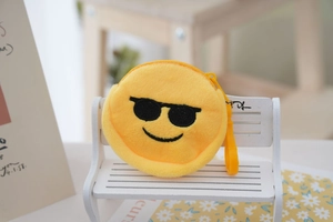 Detail showing a round yellow plush emoji purse with sunglasses on a white mini wooden bench