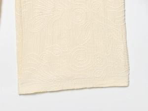 Gros plan détaillé sur tissu crème avec broderie tourbillonnante et motif texturé