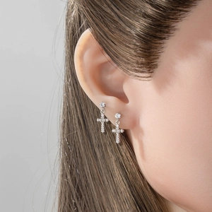 Silver stainless steel cross drop earrings with round crystal stud worn on model
