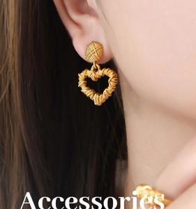 Close-up of heart-shaped gold stud earring with woven texture worn by a model