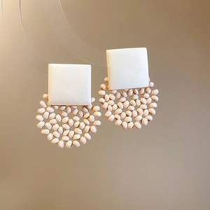 Macro detail of geometric wooden bead earrings featuring square studs and round beads