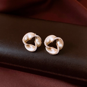 Detailed close-up of 14K gold plated twisted ribbon earrings with micro-set white zircons