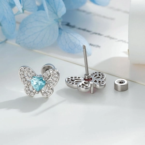 Orecchini a farfalla in argento con zircone cuore blu e cristalli su uno sfondo floreale