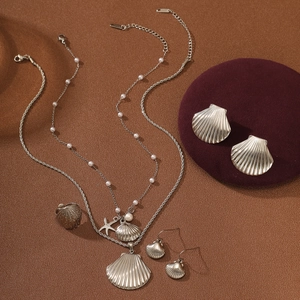 Silver ocean jewelry set with pearl, starfish, and shell pendants on a round backdrop