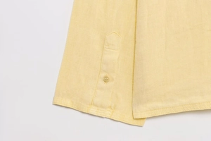 Detailed macro view of high-quality linen texture and buttons on a yellow shirt set