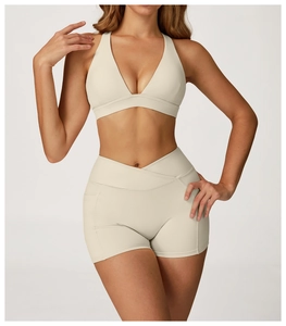 Detail of cross-back beige yoga bra and high-waisted shorts set on female model
